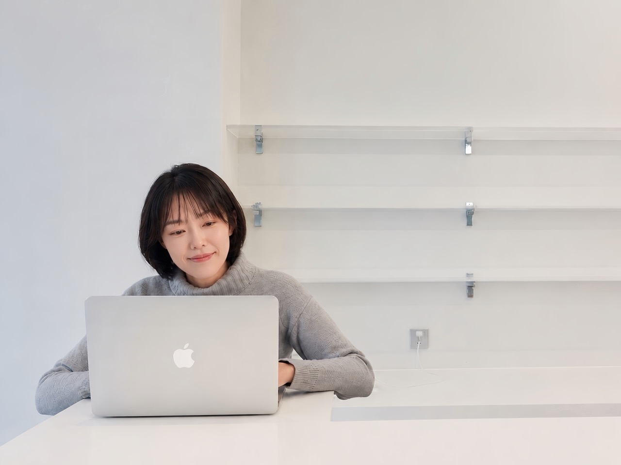 Hsin-Hsin Yuan working on a laptop in a bright white studio